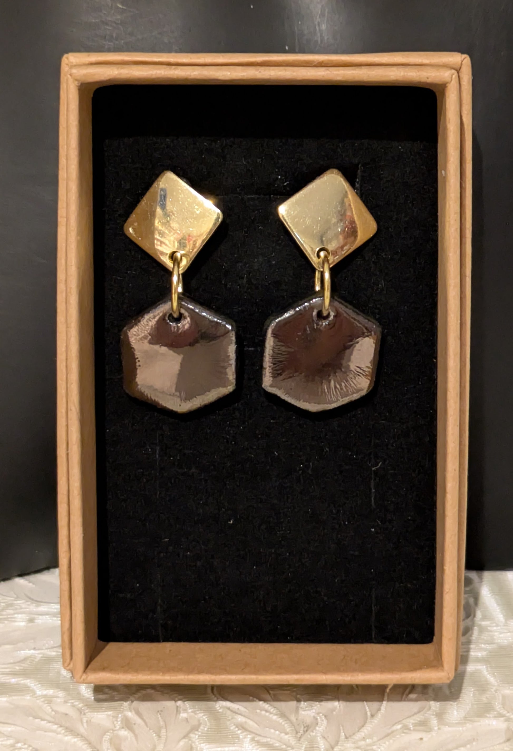 Pair of gold and bronze
 earrings in a display box.